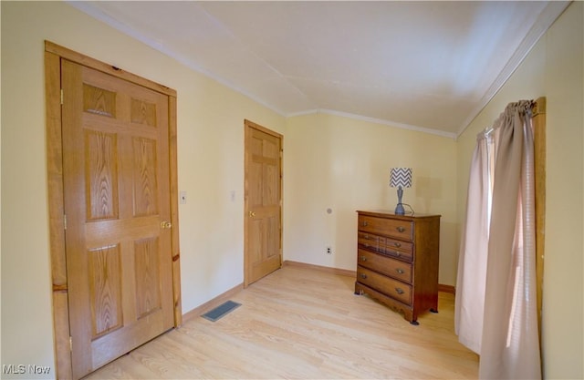 bedroom with crown molding, baseboards, visible vents, and light wood-type flooring