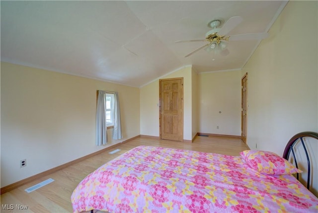 bedroom featuring visible vents, crown molding, lofted ceiling, baseboards, and light wood finished floors