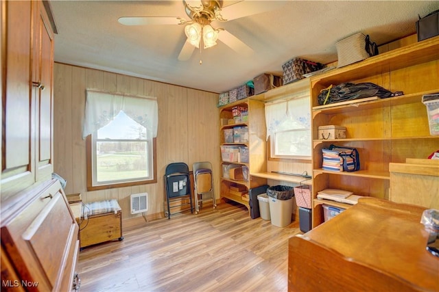 office space featuring visible vents, a ceiling fan, light wood finished floors, and wood walls