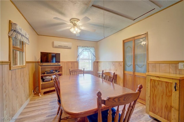 dining room featuring a wainscoted wall, a wall mounted AC, light wood-type flooring, and wood walls