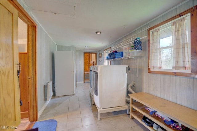 laundry room with laundry area, washer and dryer, radiator heating unit, wooden walls, and light tile patterned floors