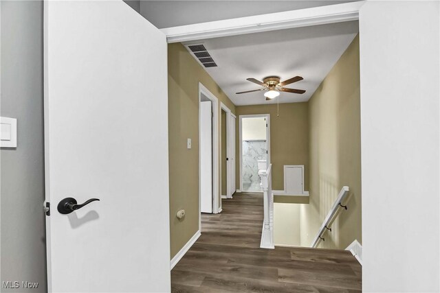 corridor featuring baseboards, visible vents, wood finished floors, and an upstairs landing