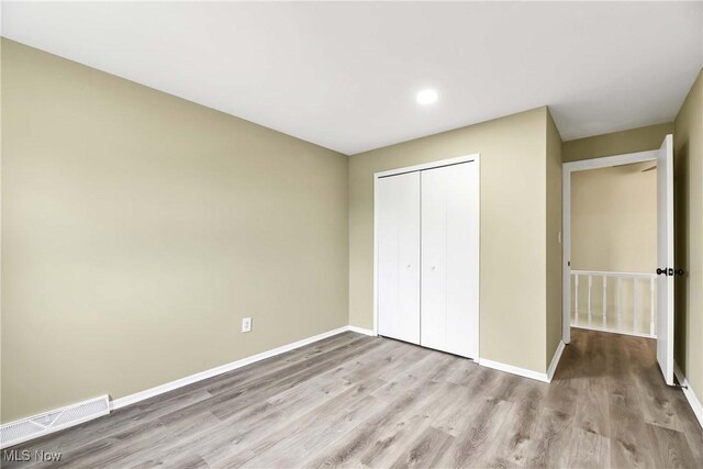 unfurnished bedroom with visible vents, a closet, wood finished floors, baseboards, and recessed lighting