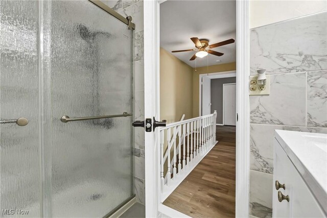 bathroom with vanity, a ceiling fan, wood finished floors, and a stall shower