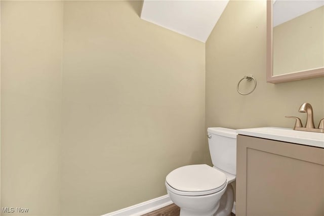 bathroom with vanity, baseboards, wood finished floors, and toilet