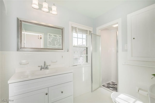 bathroom with vanity, toilet, tile walls, and a stall shower