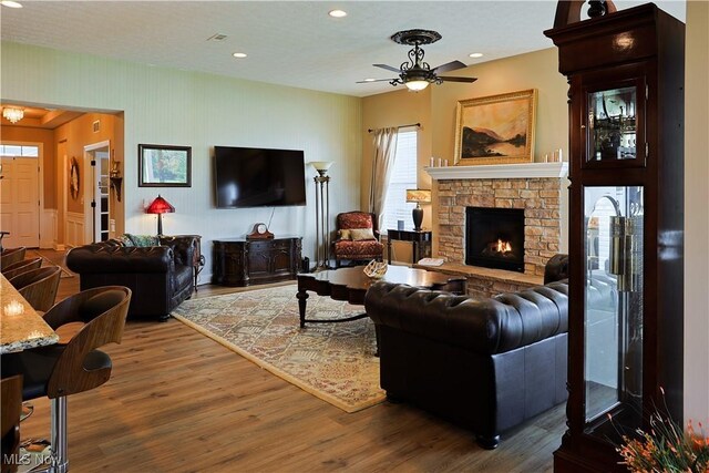 living area with ceiling fan, a fireplace, recessed lighting, and wood finished floors