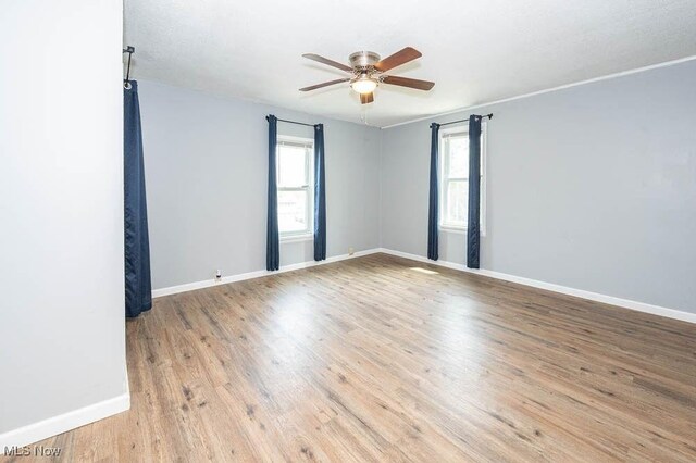 spare room featuring a ceiling fan, baseboards, and wood finished floors