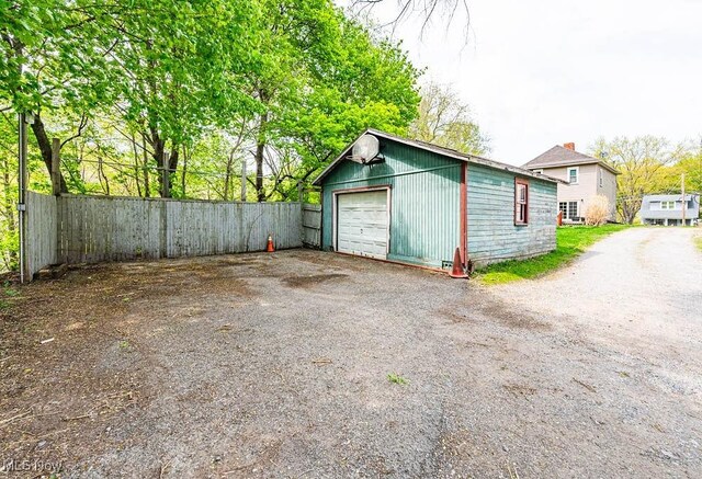 detached garage featuring fence and driveway