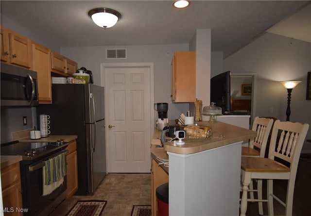 kitchen with visible vents, a peninsula, black electric range oven, a breakfast bar, and stainless steel microwave
