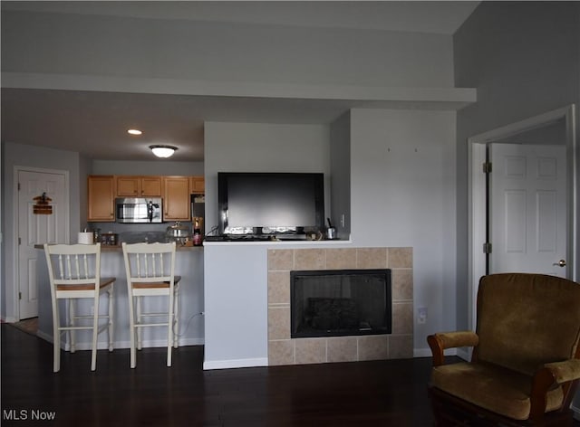 living area with recessed lighting, baseboards, dark wood finished floors, and a tile fireplace