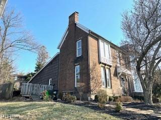 view of side of property with a yard and a chimney