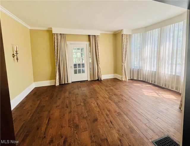 spare room featuring baseboards, visible vents, ornamental molding, and dark wood-type flooring
