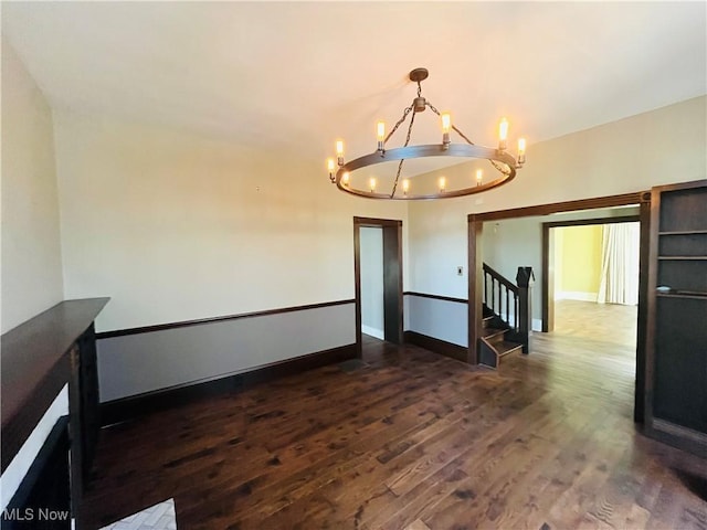 unfurnished room with baseboards, dark wood-style flooring, and a chandelier