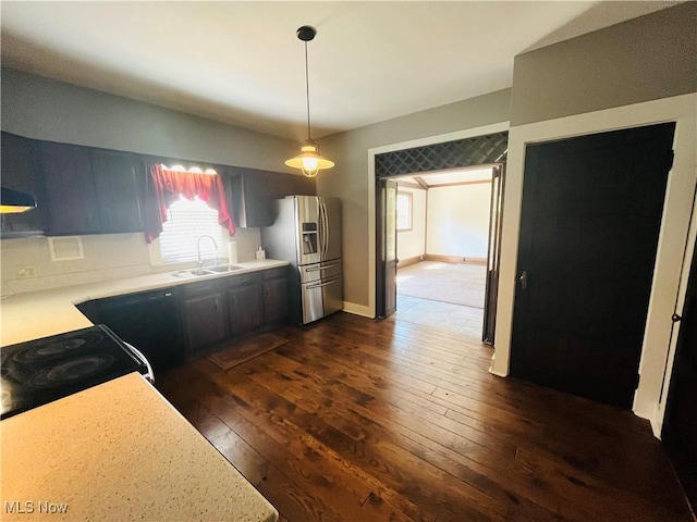 kitchen featuring stainless steel fridge, a sink, dark wood-style flooring, and light countertops