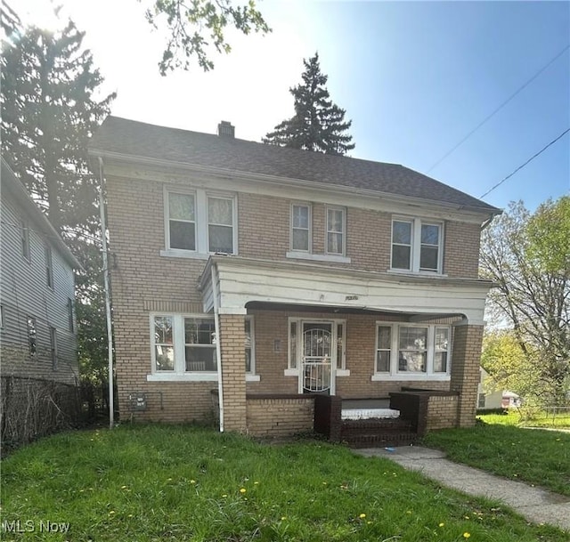 view of front of property featuring a porch, brick siding, fence, and a front yard