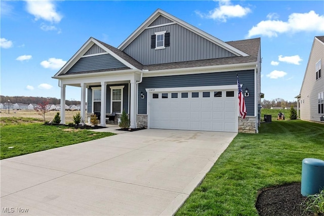craftsman-style house with board and batten siding, an attached garage, driveway, and a front lawn