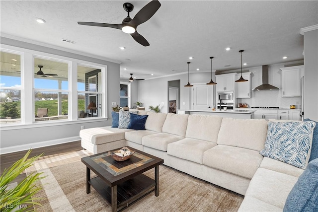 living area featuring visible vents, a ceiling fan, crown molding, and recessed lighting