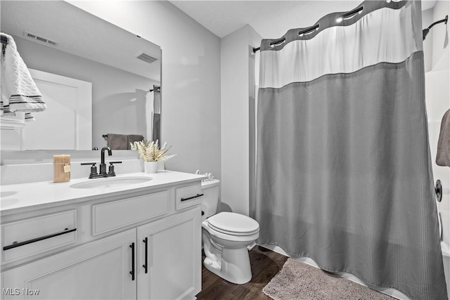 full bath featuring vanity, toilet, wood finished floors, and visible vents