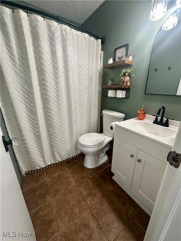 full bathroom with a shower with curtain, a textured ceiling, tile patterned floors, vanity, and toilet