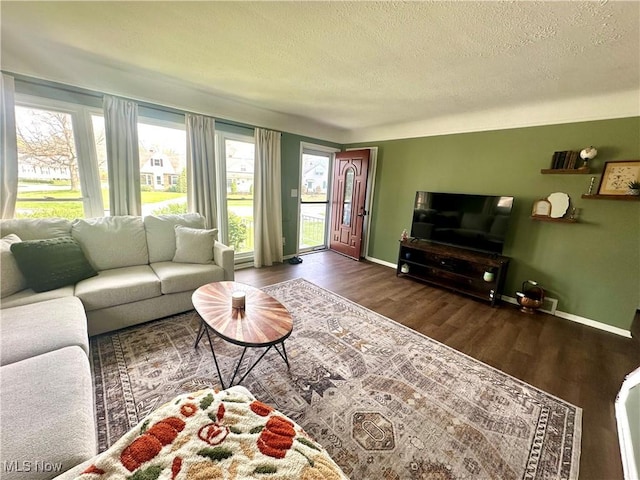 living room featuring baseboards, a textured ceiling, and wood finished floors