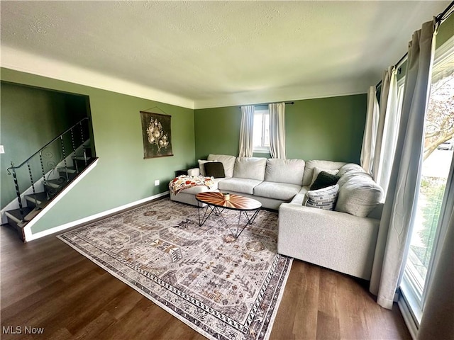 living area with a textured ceiling, baseboards, stairs, and wood finished floors