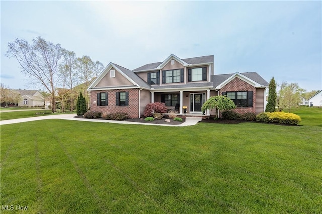 craftsman house with a porch, brick siding, and a front yard