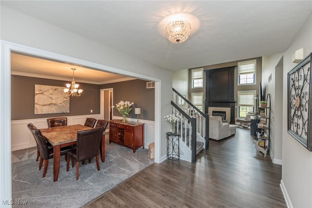 dining area featuring dark wood-style flooring, a notable chandelier, a fireplace, visible vents, and stairway