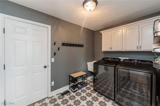 laundry area with light floors, baseboards, washing machine and dryer, and cabinet space