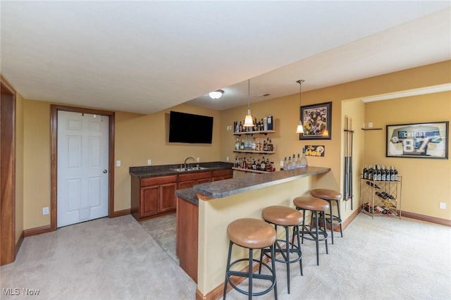 bar with indoor wet bar, decorative light fixtures, light colored carpet, and a sink