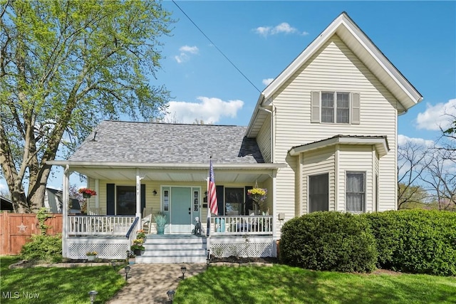traditional-style house featuring a porch, fence, and a front yard