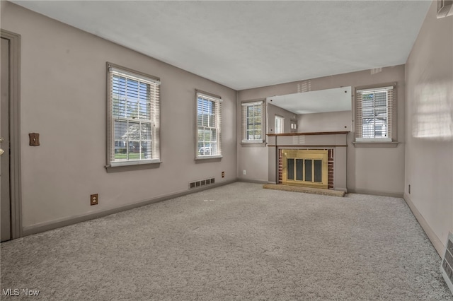 unfurnished living room featuring baseboards, plenty of natural light, carpet flooring, and a brick fireplace
