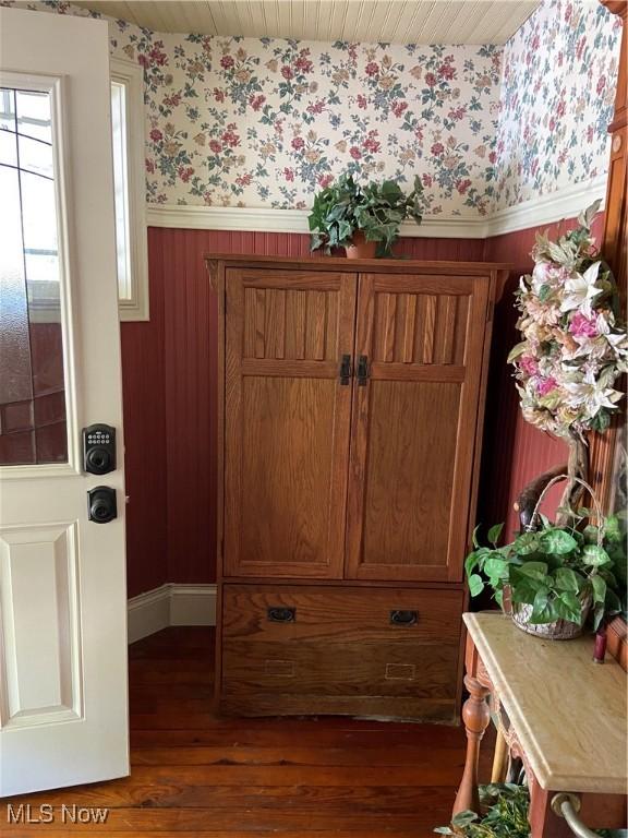 interior space featuring wood finished floors, a wainscoted wall, and wallpapered walls