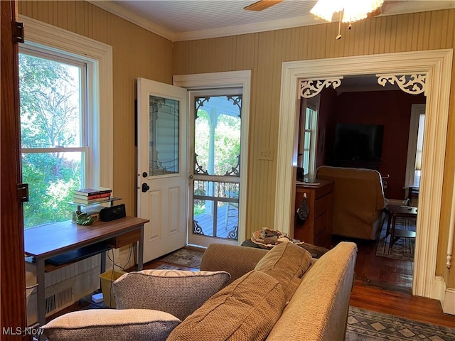 interior space with crown molding, a ceiling fan, plenty of natural light, and wood finished floors