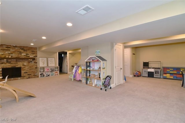 recreation room featuring carpet flooring, recessed lighting, visible vents, and a brick fireplace