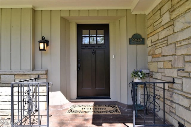 view of exterior entry featuring board and batten siding, a porch, and stone siding