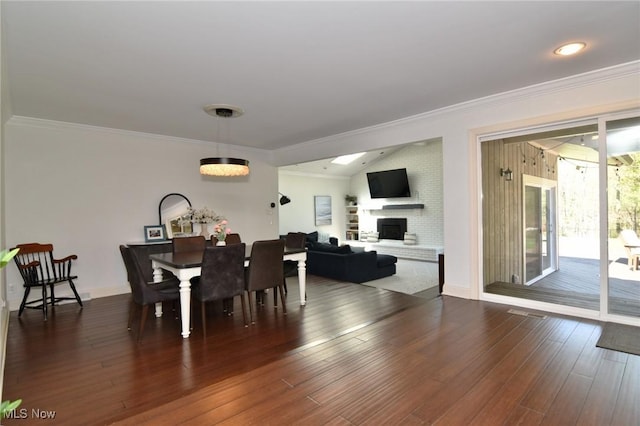dining room featuring crown molding, dark wood-type flooring, and a large fireplace
