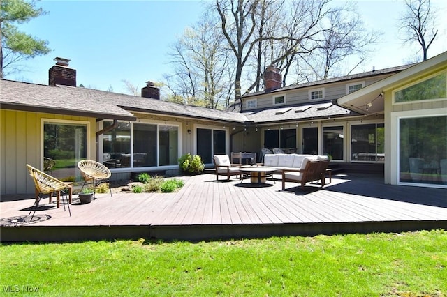 rear view of house featuring a lawn, a wooden deck, a chimney, and outdoor lounge area