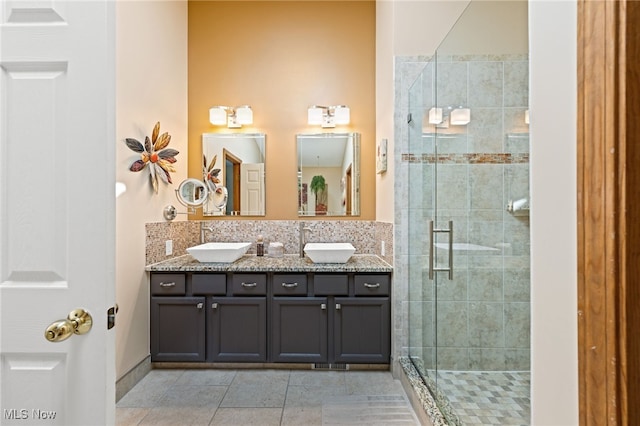 full bath with double vanity, tile patterned floors, a sink, and a stall shower