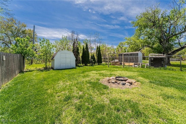 view of yard with a storage unit, an outbuilding, a fenced backyard, and an outdoor fire pit