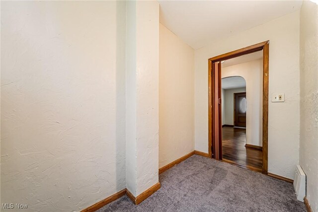 corridor with carpet floors, arched walkways, baseboards, and visible vents