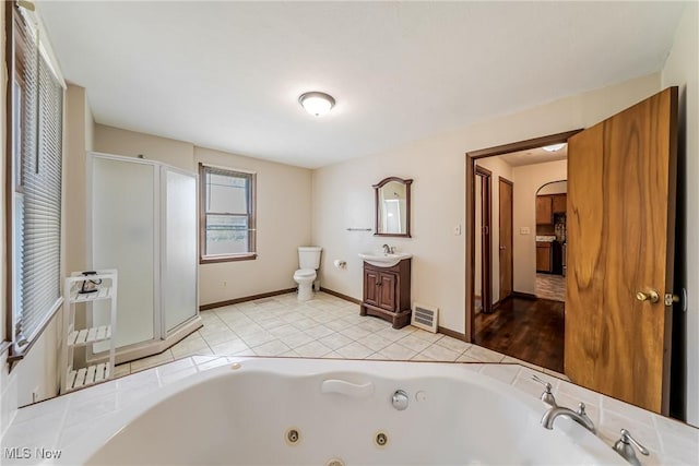bathroom with vanity, toilet, a whirlpool tub, baseboards, and a shower stall