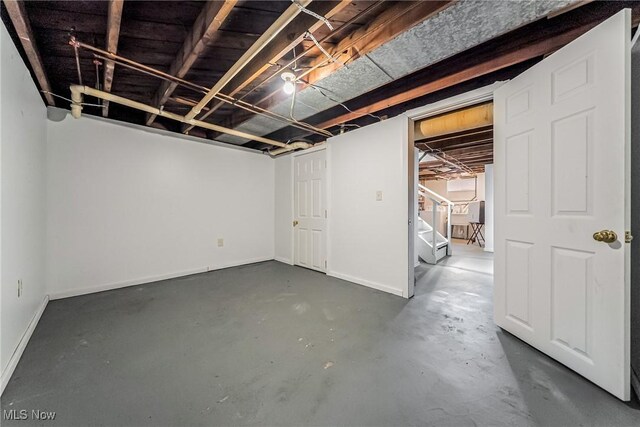 unfinished basement with baseboards and stairway
