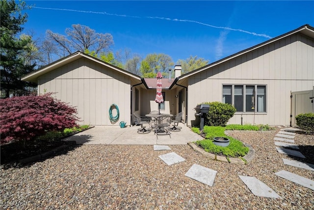 rear view of property featuring a chimney and a patio area