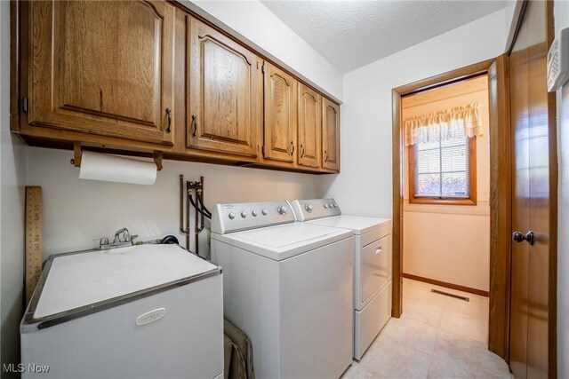 laundry area with cabinet space, a textured ceiling, baseboards, visible vents, and washer and clothes dryer