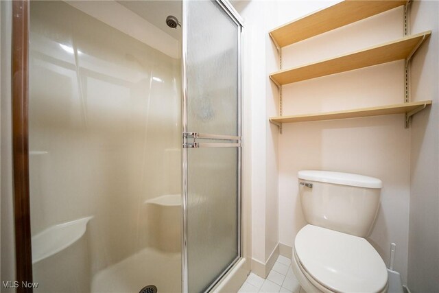 full bathroom with toilet, baseboards, a shower stall, and tile patterned flooring