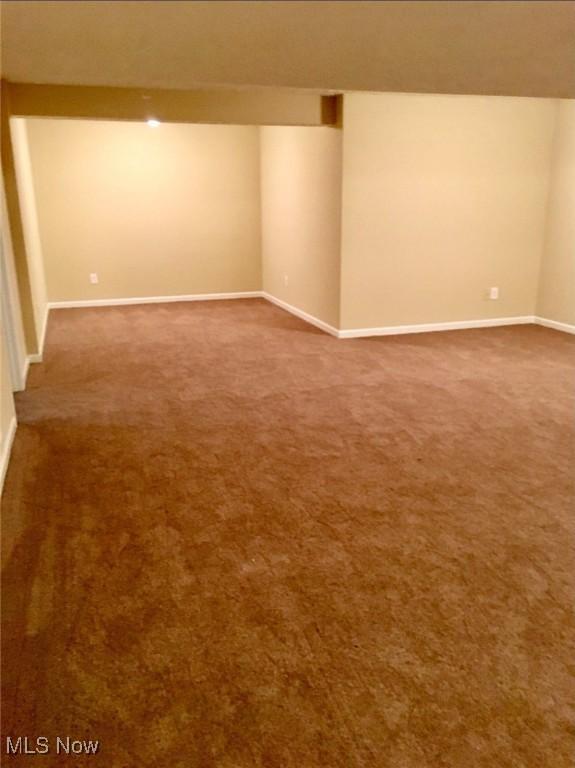 unfurnished room with dark carpet and baseboards
