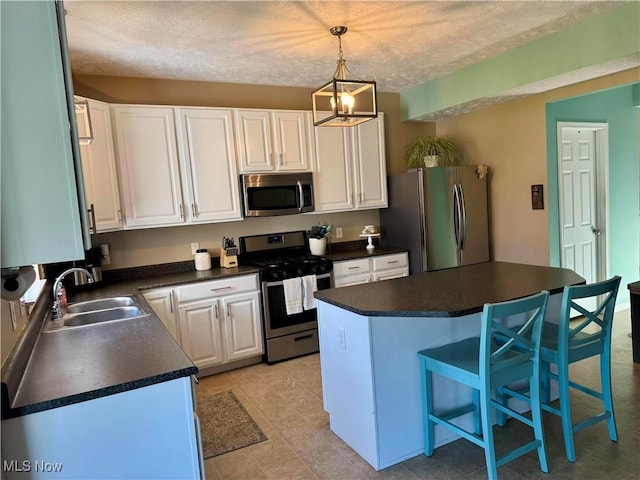 kitchen with a sink, dark countertops, white cabinets, and stainless steel appliances