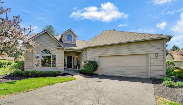 traditional home featuring roof with shingles, an attached garage, and driveway