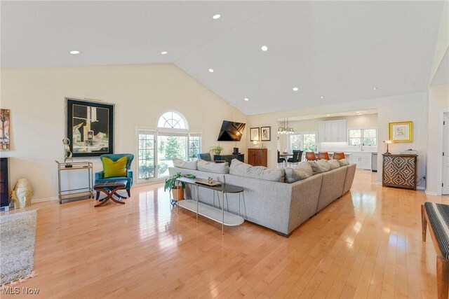 living room with high vaulted ceiling and light wood-style flooring